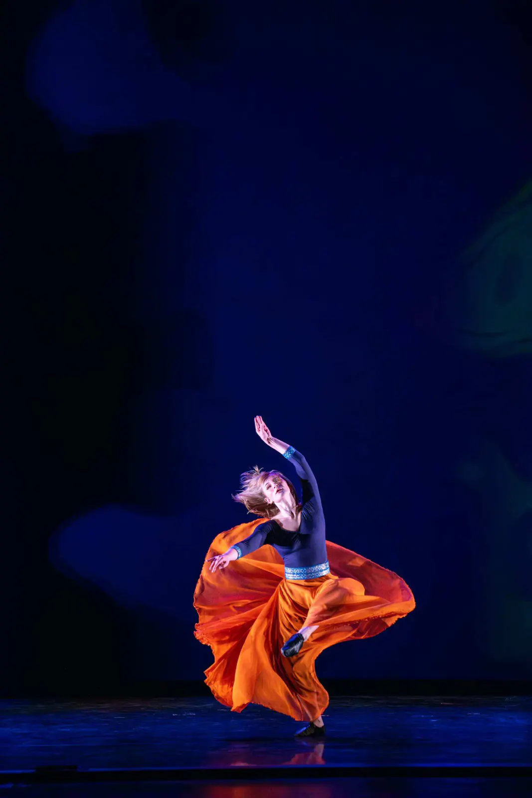 A Khazan dancer turning in a flowing orange skirt